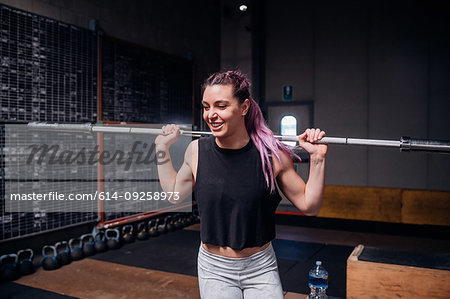 Young woman lifting weight bar in gym