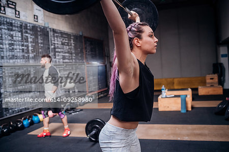 Young woman lifting barbell in gym