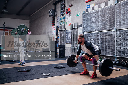 Young couple lifting barbell in gym