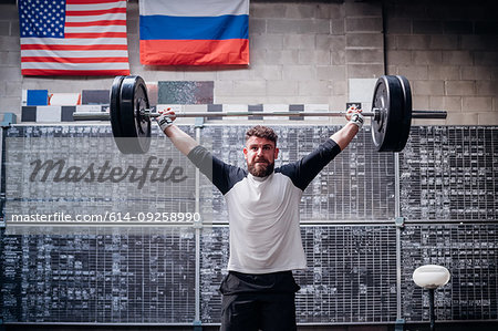 Young man lifting barbell in gym