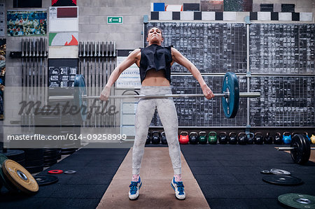 Young woman lifting barbell in gym