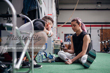 Young couple using smartphone in gym