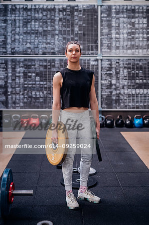 Young woman carrying weight plates in gym