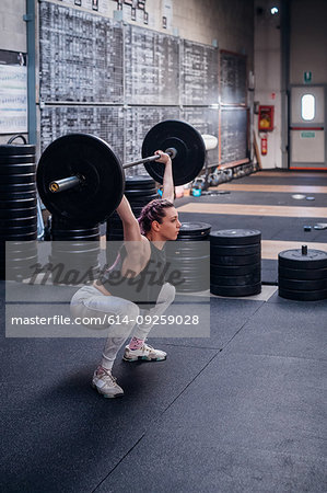 Young woman lifting barbell in gym