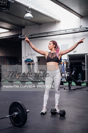 Young woman pointing fingers upwards in gym