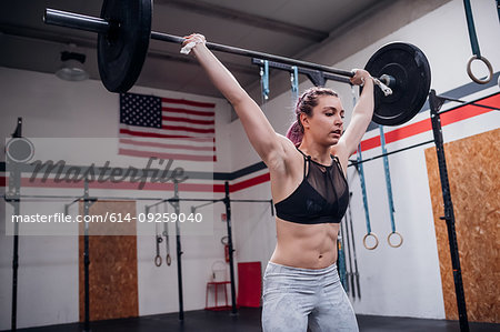 Young woman lifting barbell in gym