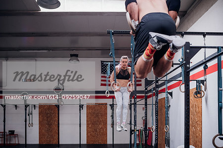 Young couple balancing on gymnastic rings in gym