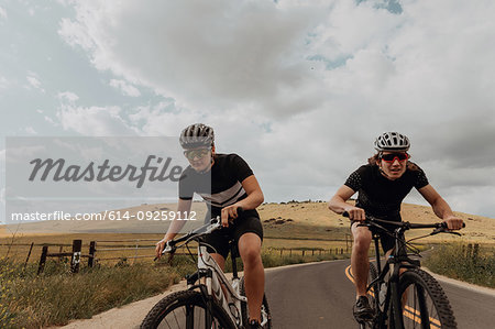 Young cycling couple cycling on rural road, Exeter, California, USA