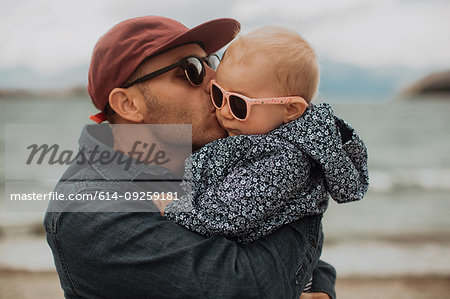 Father kissing baby on beach