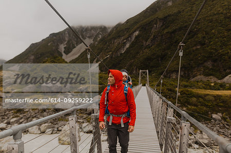 Hiker with baby crossing suspension bridge, Wanaka, Taranaki, New Zealand