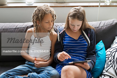 Two girls sitting on sofa looking at tablet