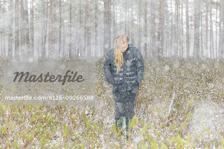 Young woman walking through a snowy forest