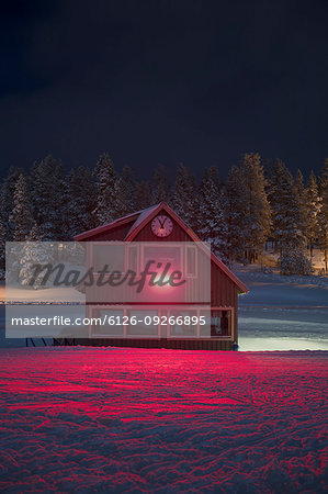 Log cabin in snow with red light