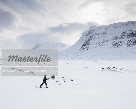 Woman skiing by mountains on Kungsleden trail in Lapland, Sweden