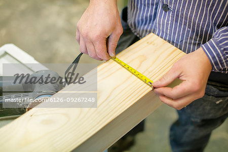 High angle view of carpenter measuring timber