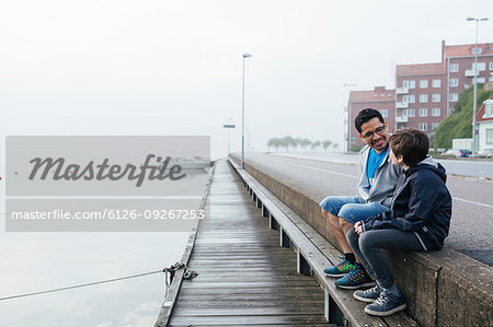 Father and son sitting by harbour