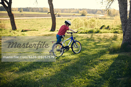 Boy pushing bicycle in on lawn
