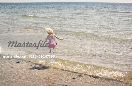 Girl jumping in wave on beach