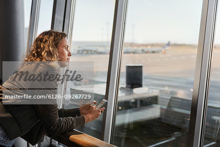 Woman with smart phone by airport window