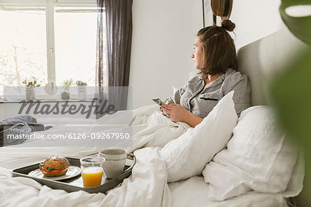 Young woman using smart phone in bed