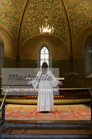 Priest in white robes standing at chancel in church