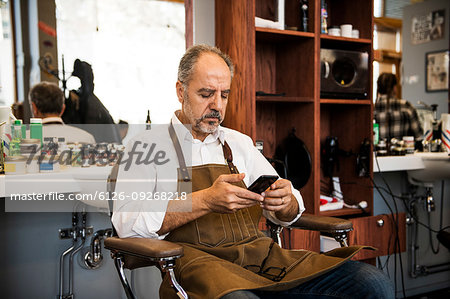 Barber using smartphone in barbershop