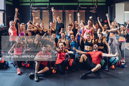 Large group of women training in gym with male trainers, posing for portrait