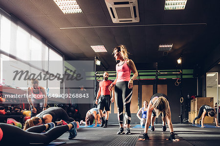 Group of women training in gym with male trainer, doing squats