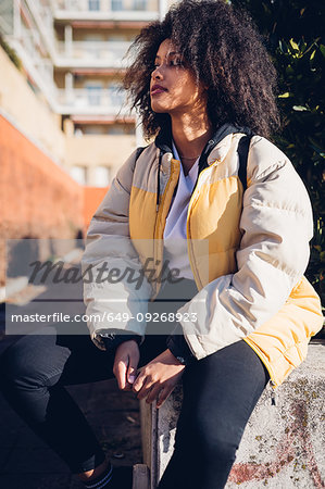 Cool young woman sitting on urban wall