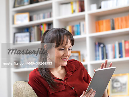 Woman relaxing at home on her digital tablet which she uses for social media, email and internet shopping