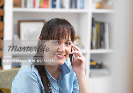 Woman relaxing and catching up with friends over the phone in her lounge