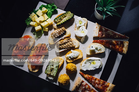 Shared platter with pizza, bruschetta and cheese on cafe table, overhead view