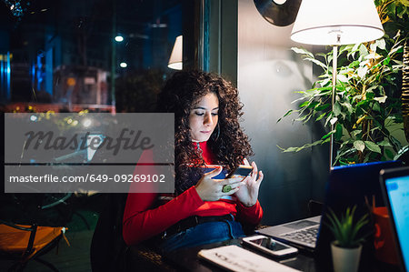 Mid adult woman looking at smartphone at cafe table