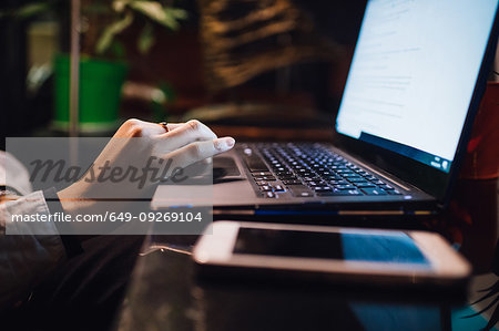 Women at cafe table typing on laptop, close up