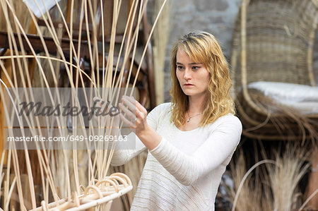 Young female basket maker weaving in workshop