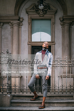 Stylish man standing on steps of period building, Milan, Italy