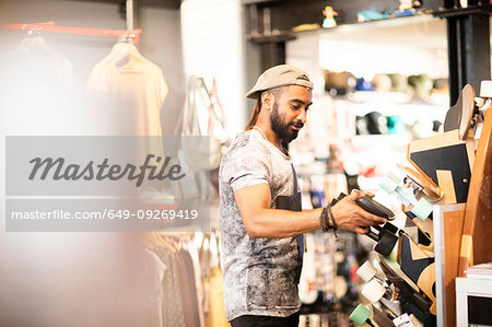 Man choosing skateboard in shop