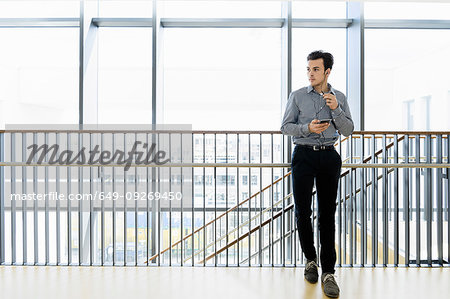 Businessman using smartphone in office corridor