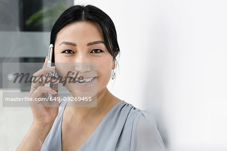 Businesswoman using smartphone against white wall in office