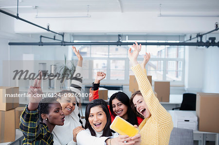Happy businesswomen celebrating new office, taking selfie