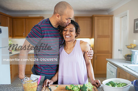 Affectionate husband hugging wife cooking in kitchen