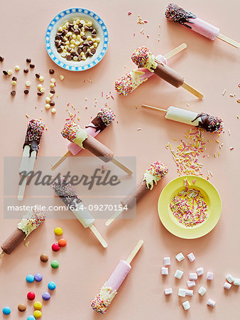 Chocolate top ice lollies and sprinkles on table