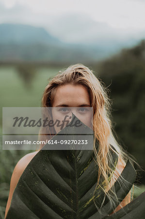 Woman in bikini holding large leaf, Princeville, Hawaii, US