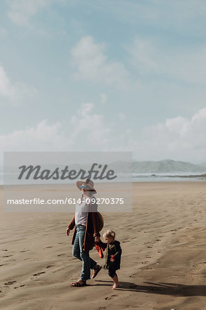 Mother and toddler walking on beach, Morro Bay, California, United States