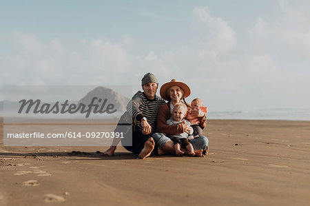 Parents and children sitting on beach, Morro Bay, California, United States