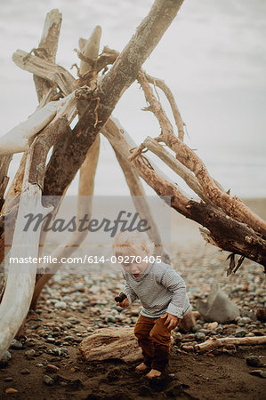 Toddler playing beside wickiup on beach