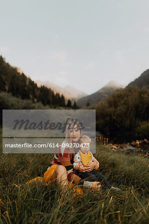 Female toddler sitting on mother's lap by rural river, portrait, Mineral King, California, USA