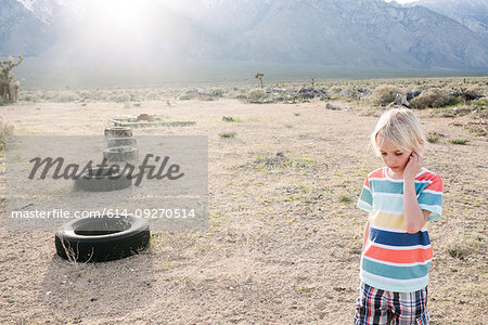 Boy exploring beside row of tyres, Olancha, California, US