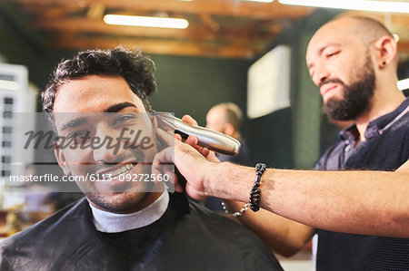 Portrait smiling young man receiving haircut at barbershop