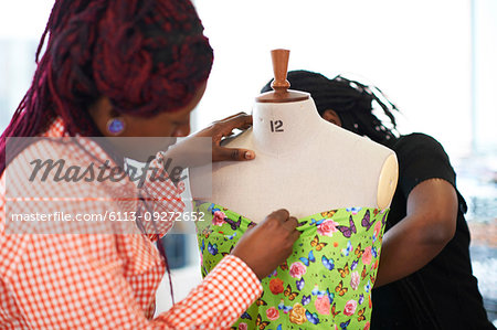 Female fashion designers pinning butterfly fabric on dressmakers model